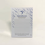 A vertical Daily Reflection notepad with a white background, decorated with dark blue stars, crescent moon, and shooting stars, featuring writing lines and prompts.