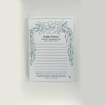 A white Daily Vision journaling notepad with a green floral vine border and black text, displayed against a clean white background.